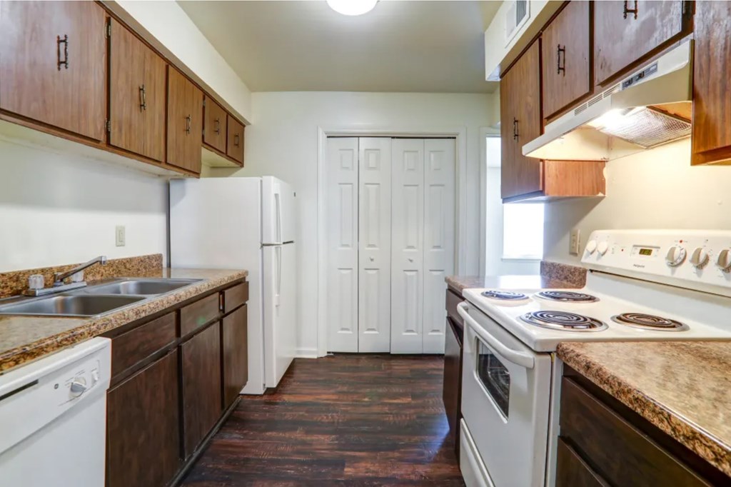 A kitchen with white appliances and brown cabinets.